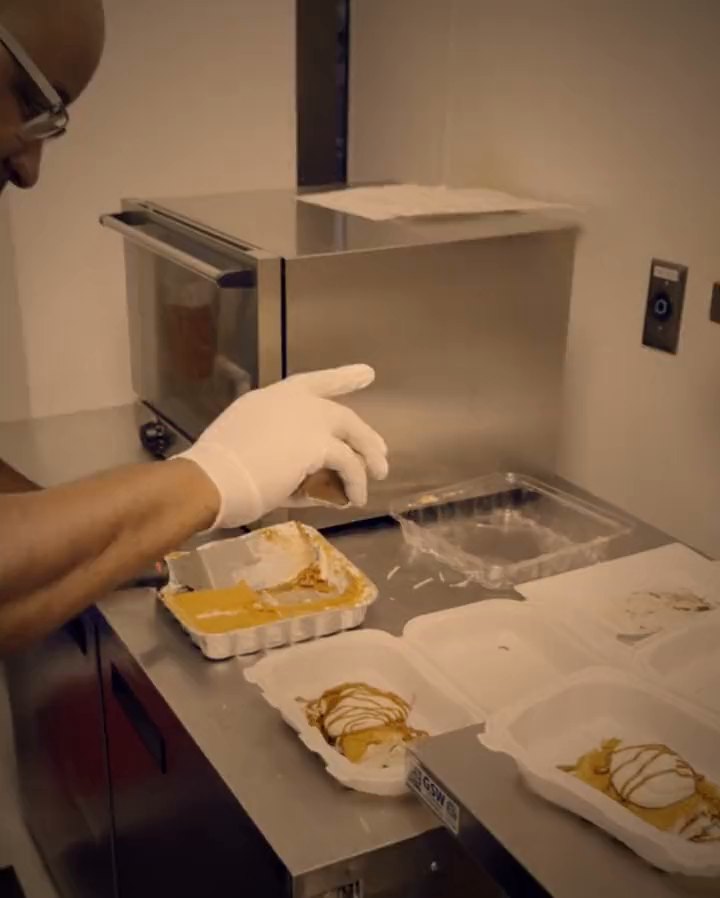 Chef Al drizzling sauce over a plated dessert, gloved and focused.