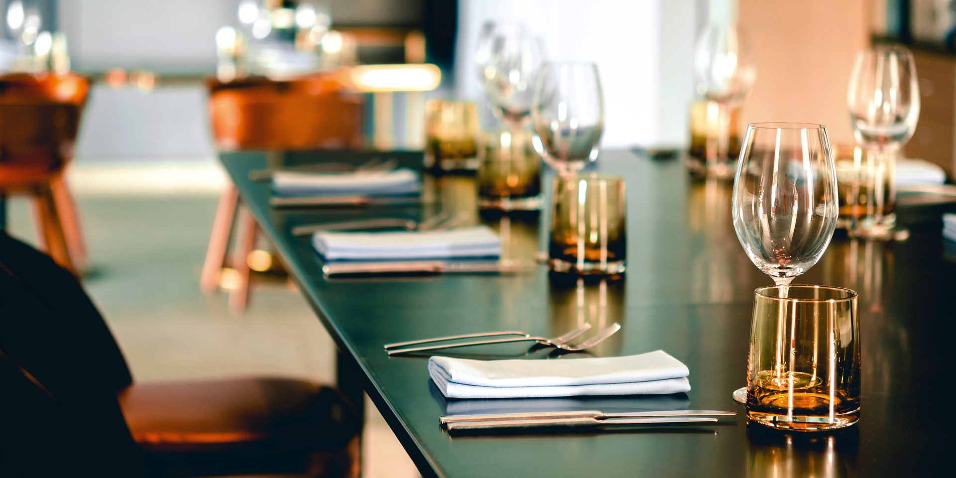 A single place setting: folded linen, dark ceramic and cutlery laid for dinner.